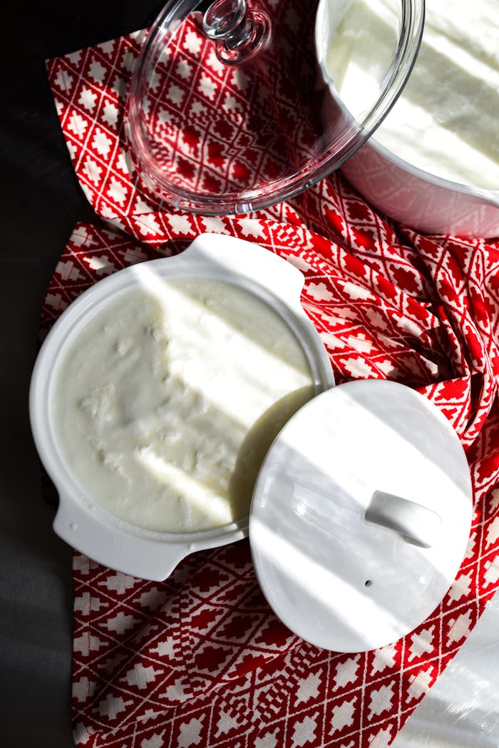 Fresh Turkish yogurt served in white dishes on a vibrant red patterned cloth, perfect for culinary presentations.