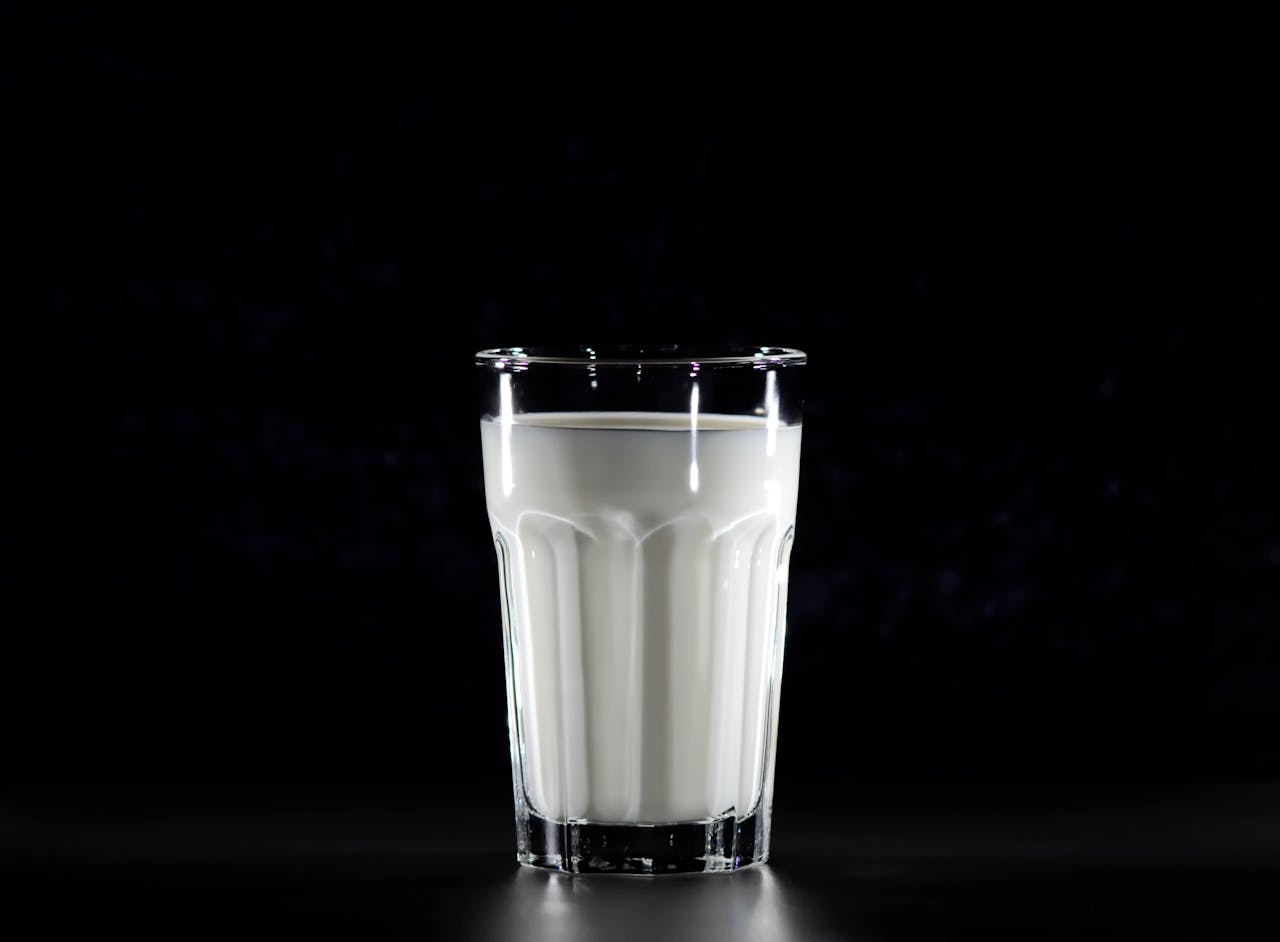 A glass of fresh milk against a black background, emphasizing simplicity and nutrition.